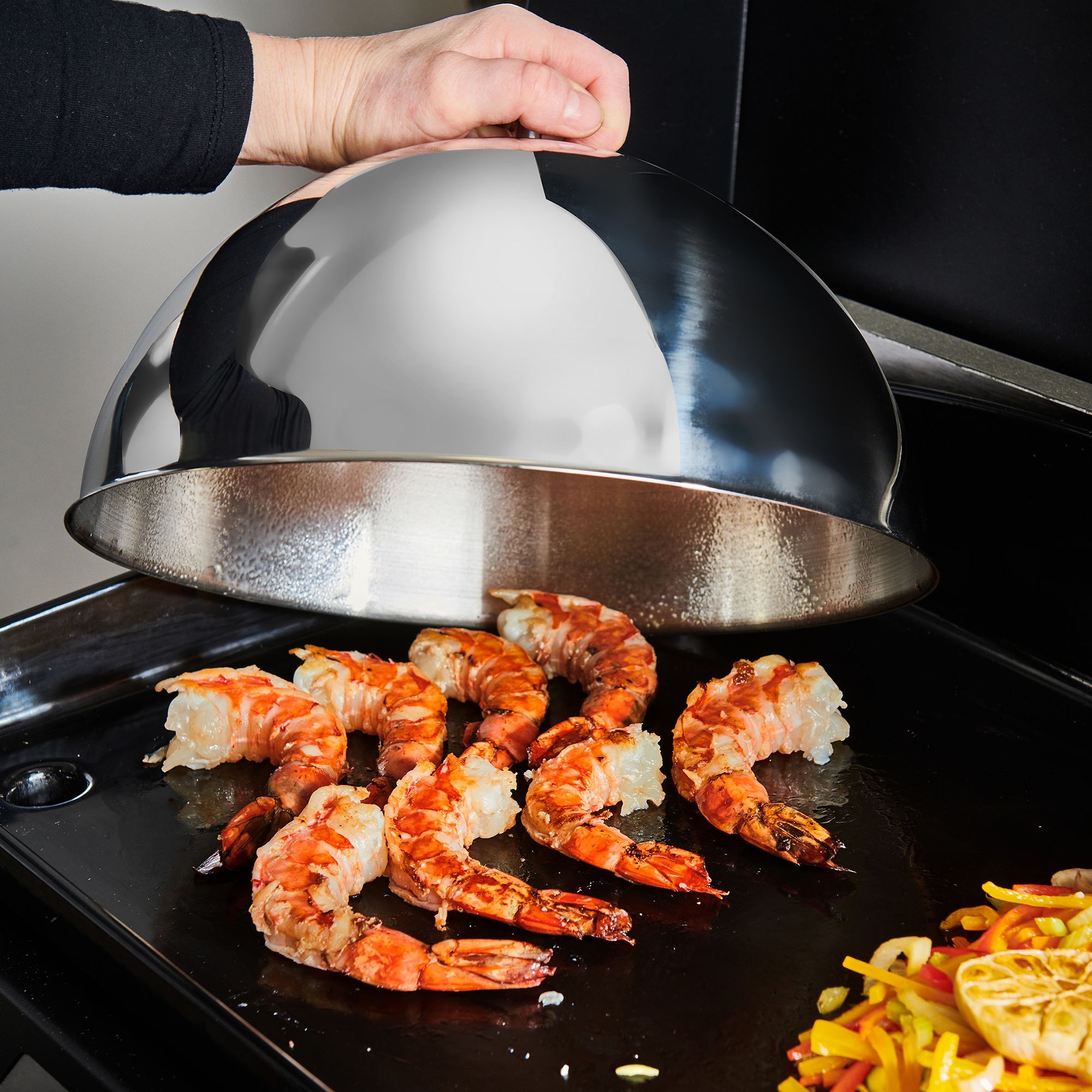 Grillglocke aus Edelstahl über gegrillten Garnelen