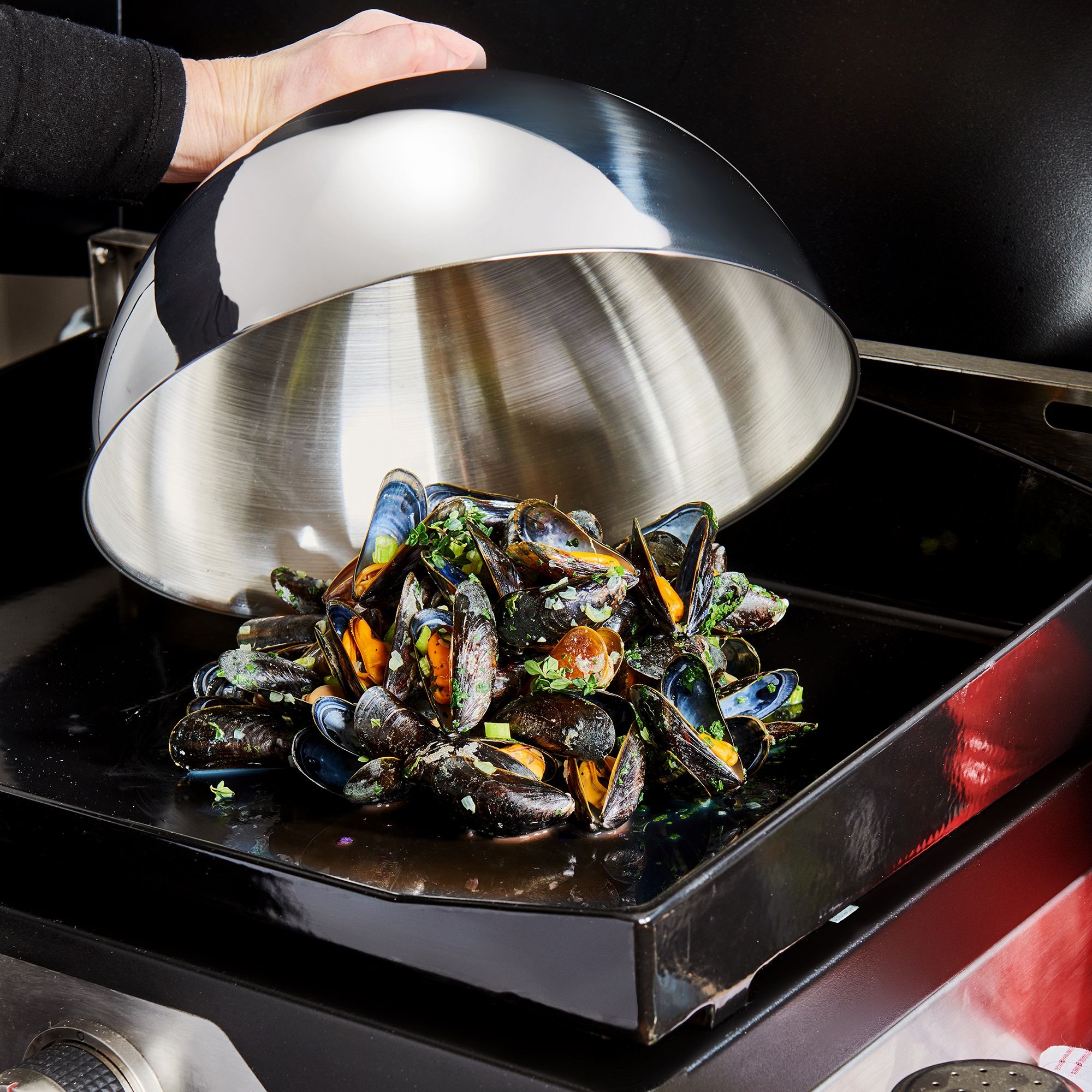 Muscheln unter Edelstahl-Glocke auf Grillplatte
